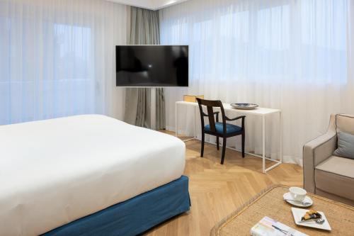 a hotel room with a bed and a chair and a tv at Hotel Morfeo in Milan