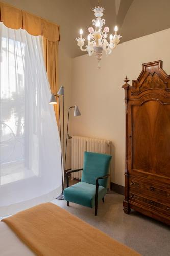 a bedroom with a green chair and a chandelier at Distilia Dimora Salentina in San Cesario di Lecce