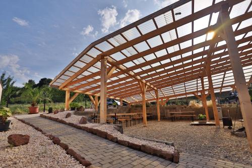 a wooden pavilion with tables and benches in a park at Margaréta Apartman és Üdülőház in Bogács