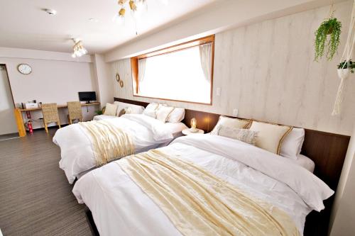 three beds in a room with white sheets at TOMMY CONDOMINIUM WAKASA 502 in Naha