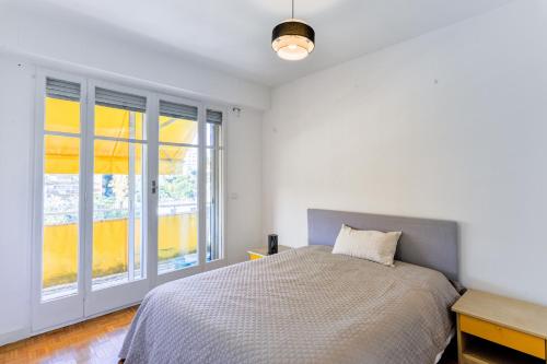 une chambre blanche avec un lit et une fenêtre dans l'établissement Le Béryl, à Nice