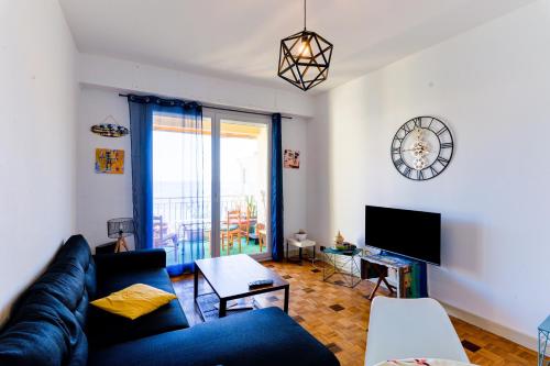 un salon avec un canapé et une horloge au mur dans l'établissement Le Béryl, à Nice