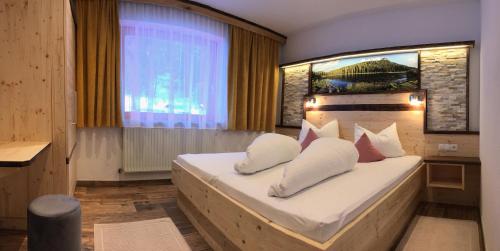 Un dormitorio con una cama con almohadas blancas y una ventana en Gästeheim Sigrid, en Nauders