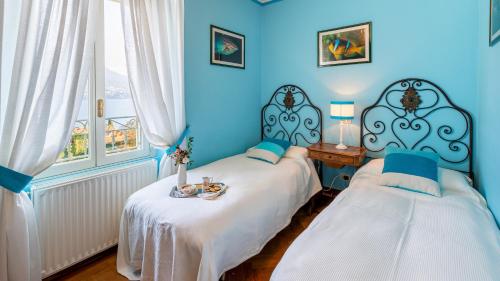 two beds in a room with blue walls and windows at Villa La Dolce 8, Emma Villas in San Siro