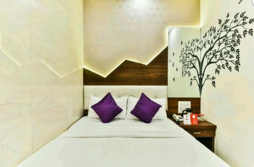 a bedroom with a white bed with purple pillows at Hotel Palace Residency near Lokmanya Tilak Terminus in Mumbai
