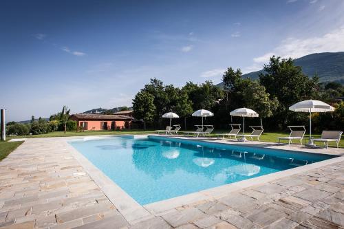 a swimming pool with chairs and umbrellas in a yard at Country House Poggio Fiorito in Assisi