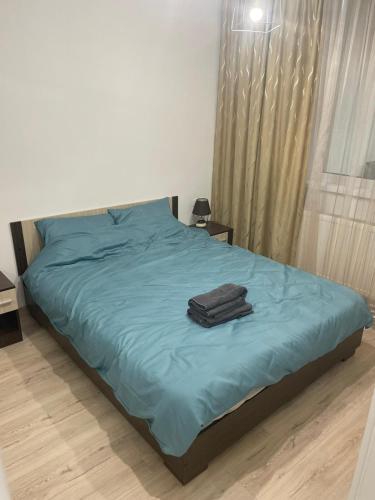 a bed with a blue blanket and a suitcase on it at Apartament centrul vechi in Baia Mare