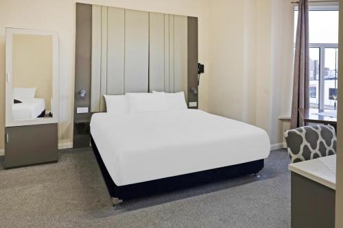 sypialnia z dużym białym łóżkiem i lustrem w obiekcie OYO The Baltimore Hotel w mieście Middlesbrough
