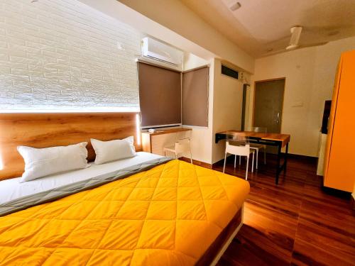 a bedroom with a large yellow bed with a desk at Stayinn Nest in Bhopal