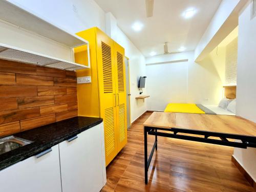 a kitchen with yellow and white cabinets and a table at Stayinn Nest in Bhopal