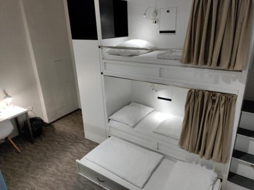 a small room with white bunk beds and a desk at Downtown Boutique Hostel in Zadar