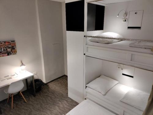 a small white room with a desk and a bed at Downtown Boutique Hostel in Zadar