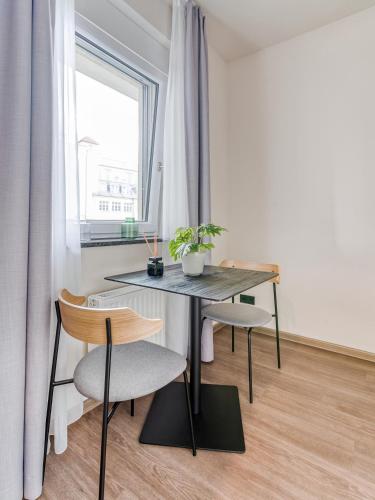a table and two chairs in a room with a window at Limehome Leipzig Oelßner's Hof in Leipzig