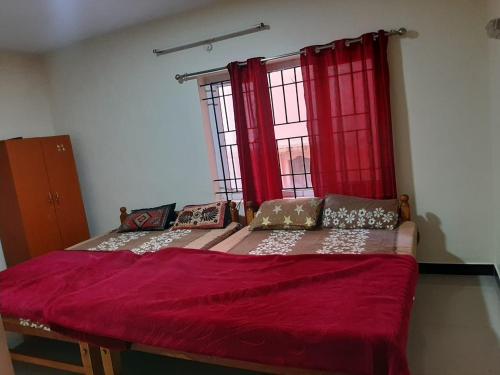 a bedroom with two beds with red curtains at jack N jill holidays inn in Ooty