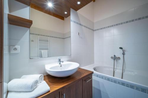 a white bathroom with a sink and a tub at Apartment Doky D8 - Lipno Home in Lipno nad Vltavou