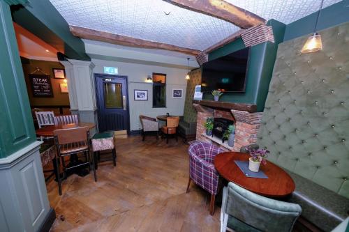 a restaurant with a fireplace and tables and chairs at Governors House by Greene King Inns in Cheadle Hulme