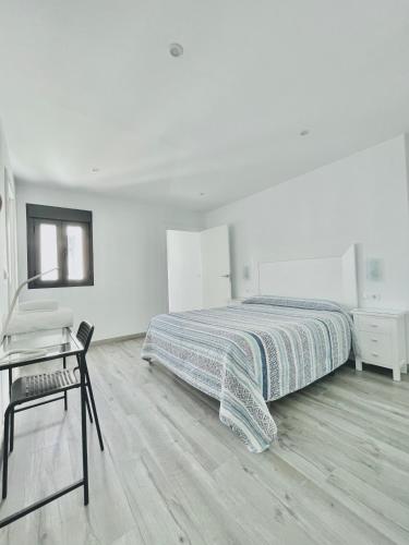a white bedroom with a bed and a desk at Apartamento Loft Lucena in Lucena