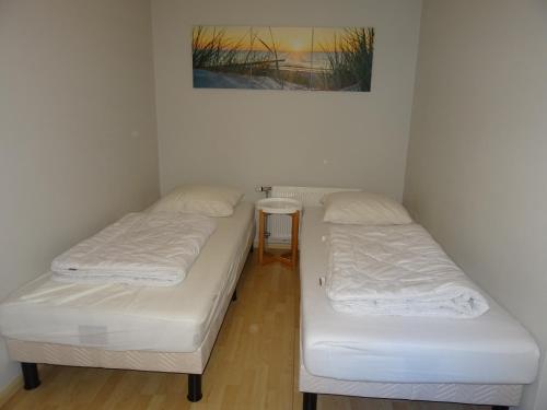 two twin beds in a room with a table at Kustverhuur, Appartement aan Zee, Prachtig appartement op de begane grond PS 13-001 in Breskens