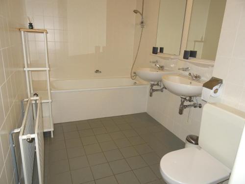a bathroom with two sinks and a toilet and a tub at Kustverhuur, Appartement aan Zee, Prachtig appartement op de begane grond PS 13-001 in Breskens