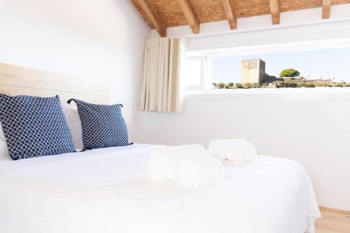 una camera da letto con un letto bianco con cuscini blu e una finestra di A BURGUESA - GUESTHOUSE a Castelo de Vide