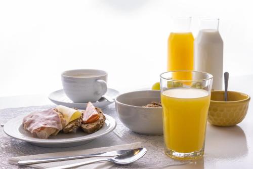 a table with a plate of food and a glass of orange juice at A BURGUESA - GUESTHOUSE in Castelo de Vide