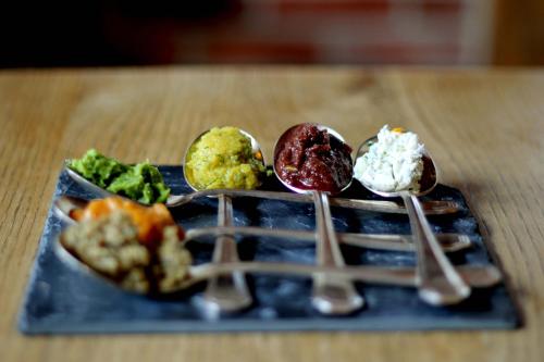 a blue plate with four different types of food on spoons at Alter Hof am Elbdeich in Unbesandten