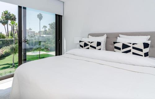 a white bedroom with a large bed and a window at GG- Modern townhouse, families & couples only in Marbella