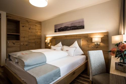 a bedroom with a large white bed and a chair at Der WALZL in Innsbruck