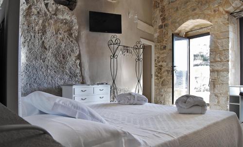 a bedroom with a white bed and a tv on the wall at Borgo Hedone in Scicli