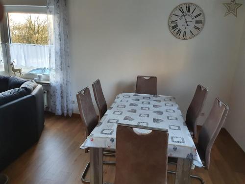 une table à manger avec des chaises et une horloge murale dans l'établissement Ferienhaus Trudi, à Winterberg