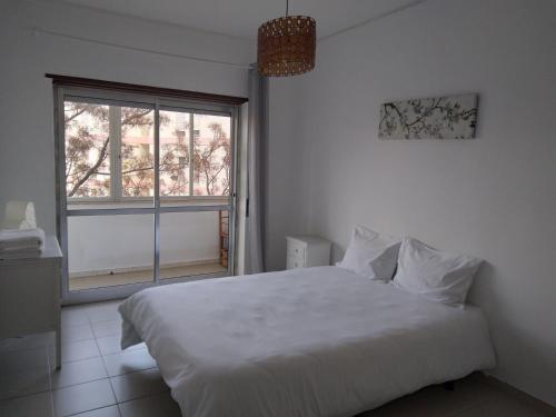 a bedroom with a white bed and a window at Casa do MIGUEL- 2 BEDROOM APARTMENT in Faro