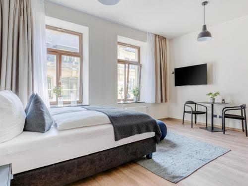 a white bedroom with a bed and a desk at Limehome Leipzig Oelßner's Hof in Leipzig
