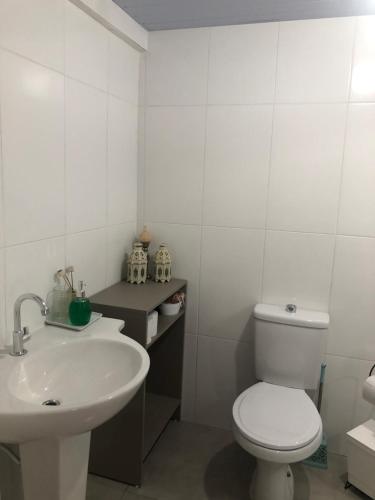 a white bathroom with a toilet and a sink at Apartamento duplo com banheiro privativo in São José
