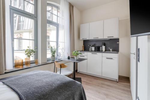 a kitchen with white cabinets and a table in a room at Limehome Leipzig Oelßner's Hof in Leipzig