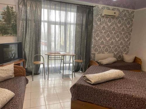a bedroom with two beds and a table and a window at 4 Seasons in Boryspilʼ
