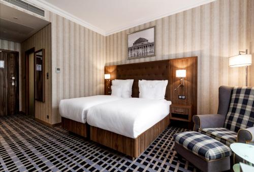 a hotel room with a large bed and a chair at Hotel Grand City Wrocław in Wrocław
