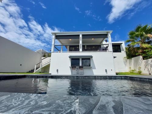 a house with a swimming pool in front of a house at Villa Pluton - Meublé de tourisme 4 étoiles in Saint-Gilles les Bains