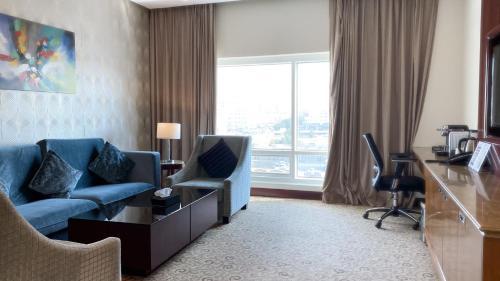a hotel room with a couch and a desk and a window at Velvet Hotel Jeddah in Jeddah