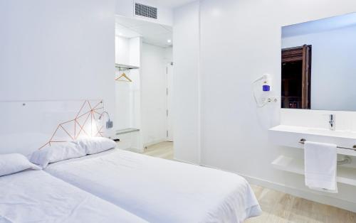a white bedroom with a bed and a sink at AMC Granada Hostal in Granada