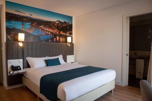 a hotel room with a bed, desk and a painting on the wall at Hotel Porto Interface Trindade By Kavia in Porto