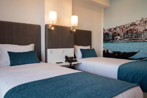 two beds in a hotel room with a view of the water at Hotel Porto Interface Trindade By Kavia in Porto