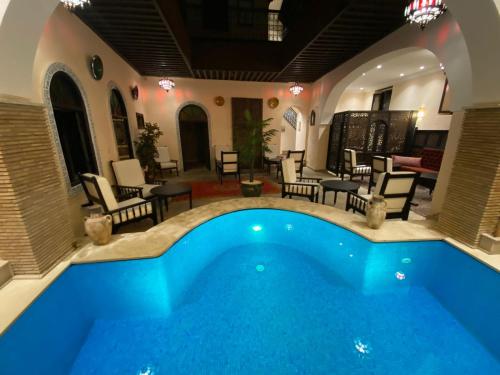 梅克內斯的住宿－Riad Zyna，庭院内的游泳池,配有椅子和桌子