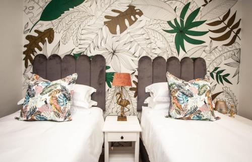 a bedroom with two beds and a wall with plants at The view 42 in Jeffreys Bay