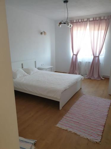 a white bedroom with a bed and a window at Casuta de la Munte in Sfodea