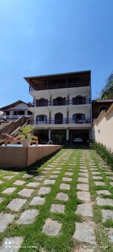 a building with a grass yard in front of it at Praia Virgem Hostel in Rio das Ostras