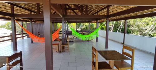 a porch with chairs and hammocks on a house at Praia Virgem Hostel in Rio das Ostras