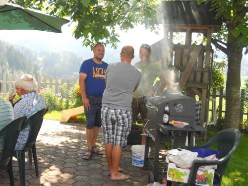 a group of people standing around a grill at Familienbauernhof Imitz, Ferienwohnung in Spital am Pyhrn