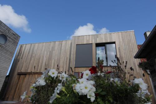a wooden building with flowers in front of it at De Panne - Adinkerke - 't Voetbrugsje comfortabele nieuwbouw in De Panne