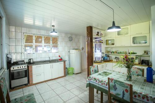 a kitchen with white cabinets and a table in it at Caiowa Floripa guesthouse in Florianópolis