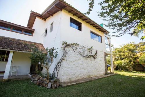 a white house with a tree in the yard at Caiowa Floripa guesthouse in Florianópolis